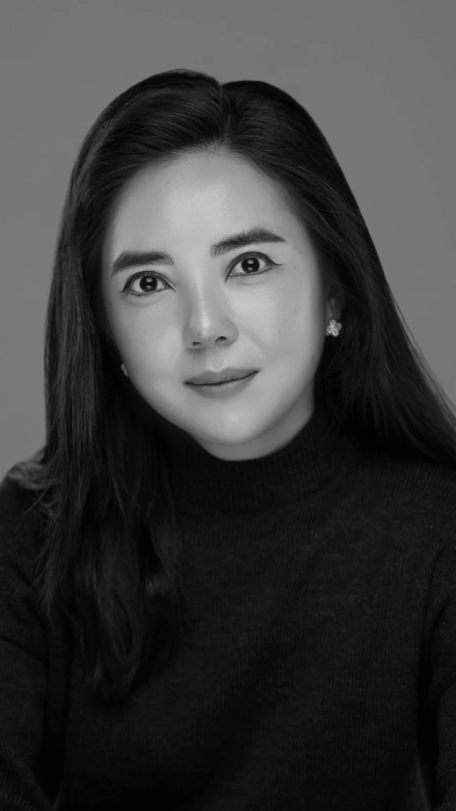 회색 배경에서 긴 생머리에 검정 니트를 입은 흑백 프로필 사진