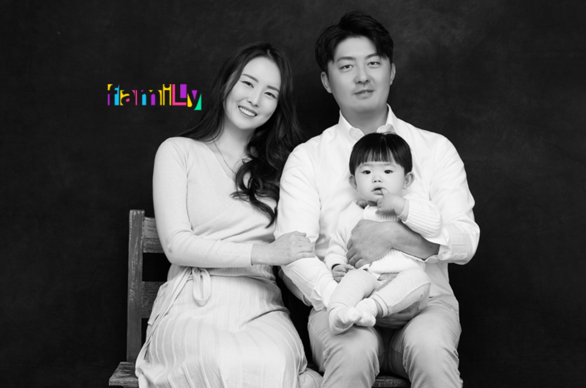 검은 배경 앞 나무 의자에 앉은 두 사람 중 한 명이 한 명을 안은 흑백 사진