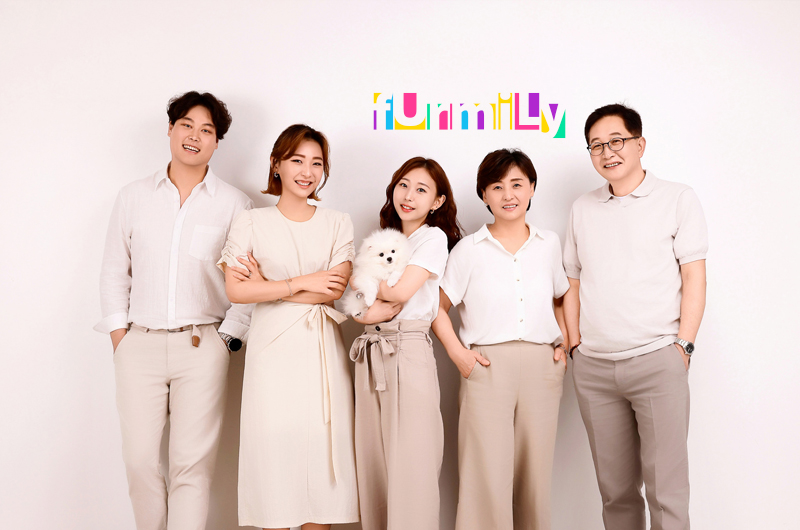 베이지·흰 옷을 맞춰 입고 선 다섯 사람, 가운데 한 명이 흰 강아지를 안음
