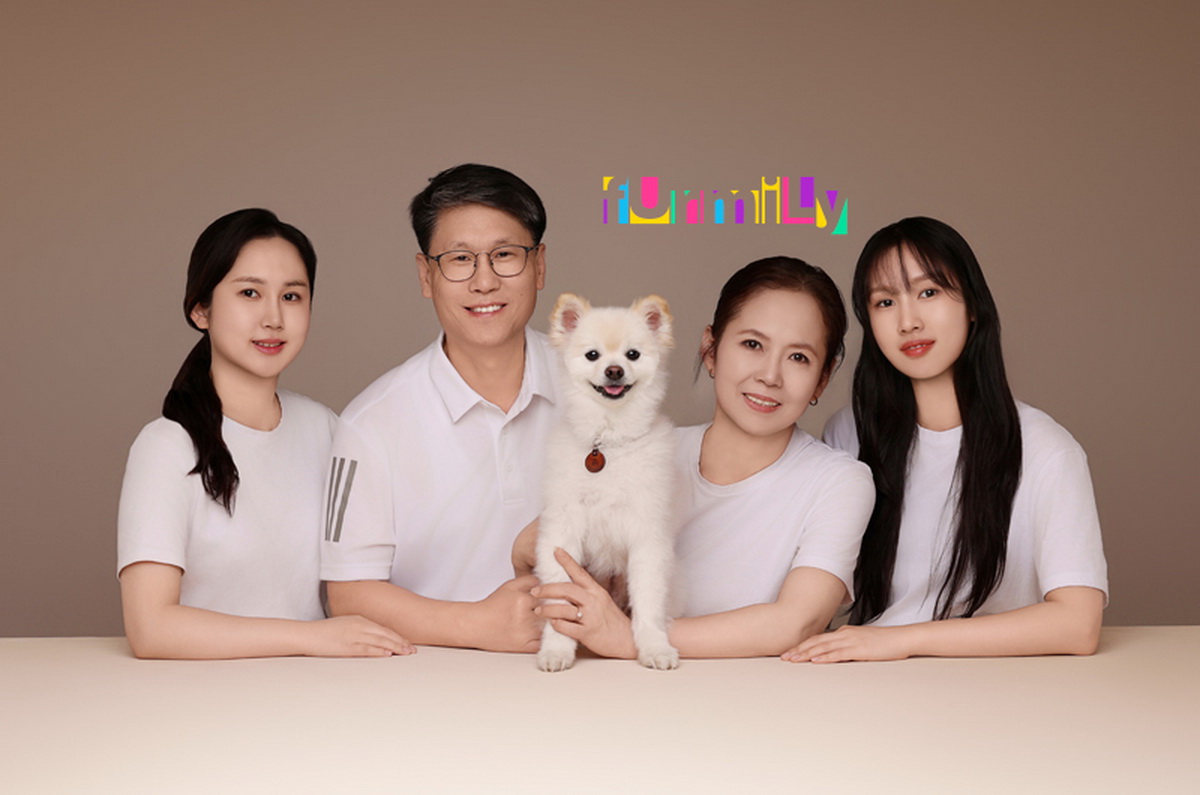 흰 상의를 맞춰 입고 테이블 앞에 앉은 네 사람과 가운데 흰 강아지, 영문 글자