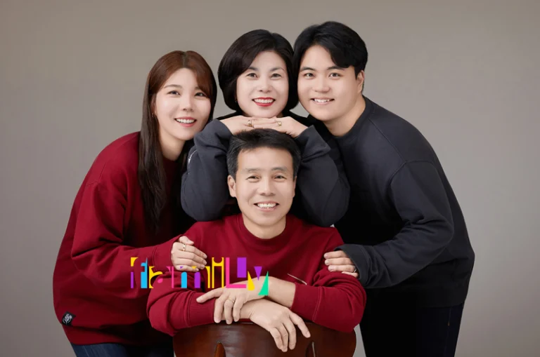 회색 배경 앞 빨강·남색 니트 차림의 네 사람, 가운데 영문 FAMILY 글자