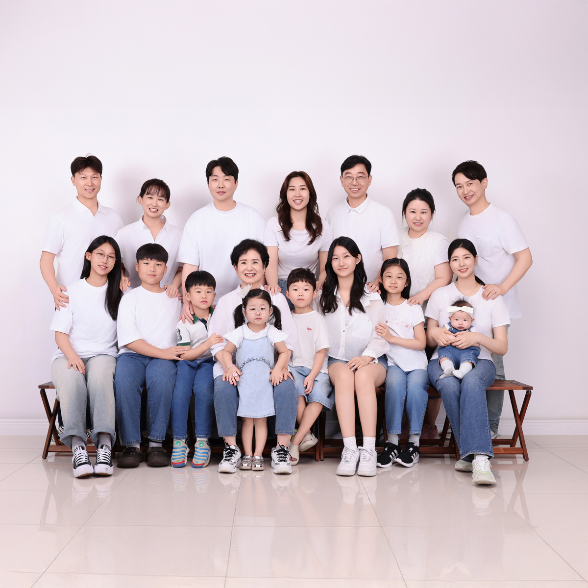 흰 상의와 청바지를 맞춰 입고 벤치 앞뒤 두 줄로 모인 열여섯 명의 단체 사진