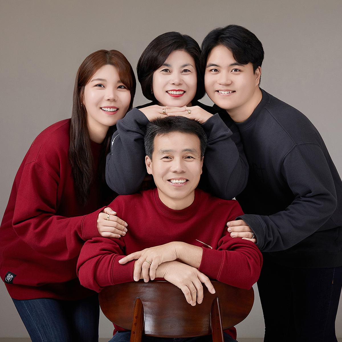 나무 벤치에 앉아 가운데를 손가락으로 가리키는 세 사람과 회색 강아지