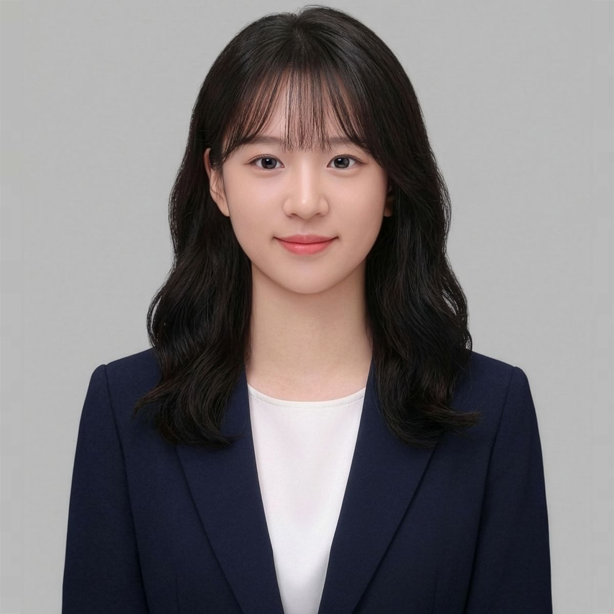 앞머리 있는 긴 머리에 남색 재킷을 입은 인물의 회색 배경 증명사진