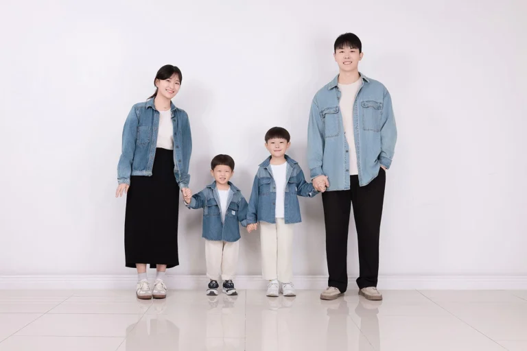 청재킷을 맞춰 입고 흰 벽 앞에 나란히 서서 손을 잡은 네 사람