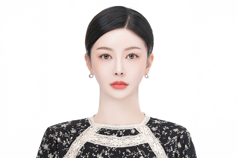 쪽진 머리에 레이스 깃 꽃무늬 상의를 입은 인물의 흰 배경 증명사진
