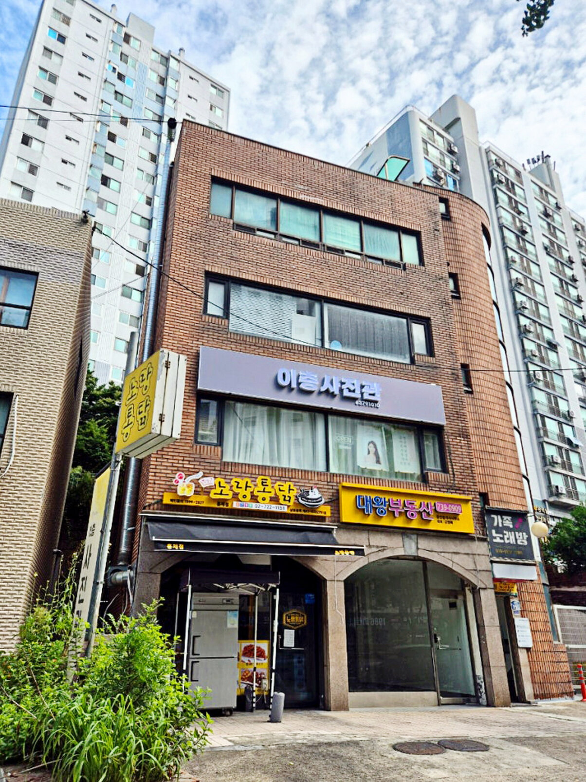3층에 이층사진관 간판이 걸린 붉은 벽돌 건물 앞 거리 모습