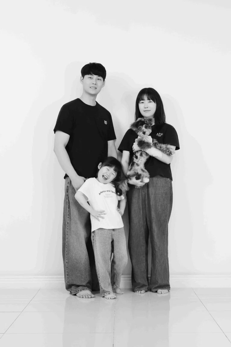 검은 티셔츠와 청바지 차림의 세 사람 중 한 명이 강아지를 안은 흑백 사진