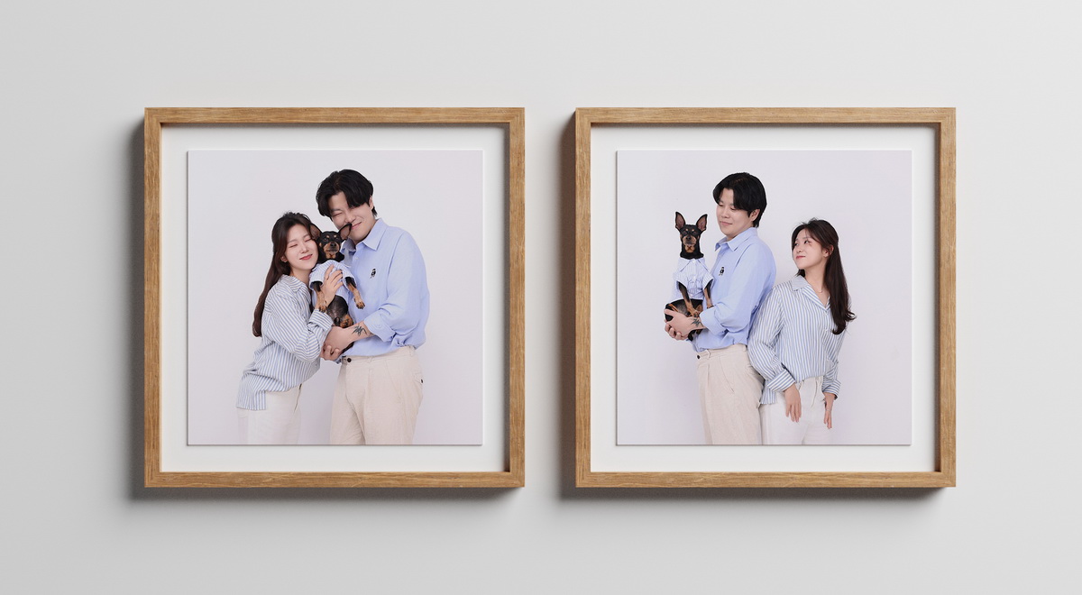 셔츠 입은 강아지를 안은 두 사람 사진 두 장이 나무 액자에 걸린 연출 이미지