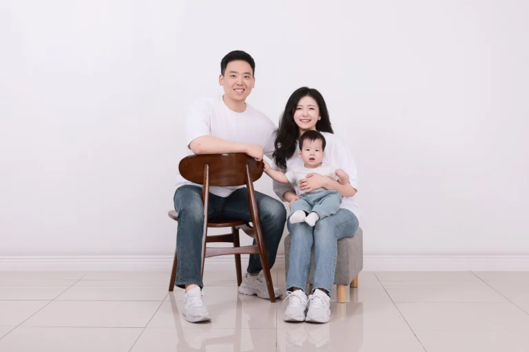의자와 스툴에 앉아 아기를 안은 어른 두 명의 가족사진