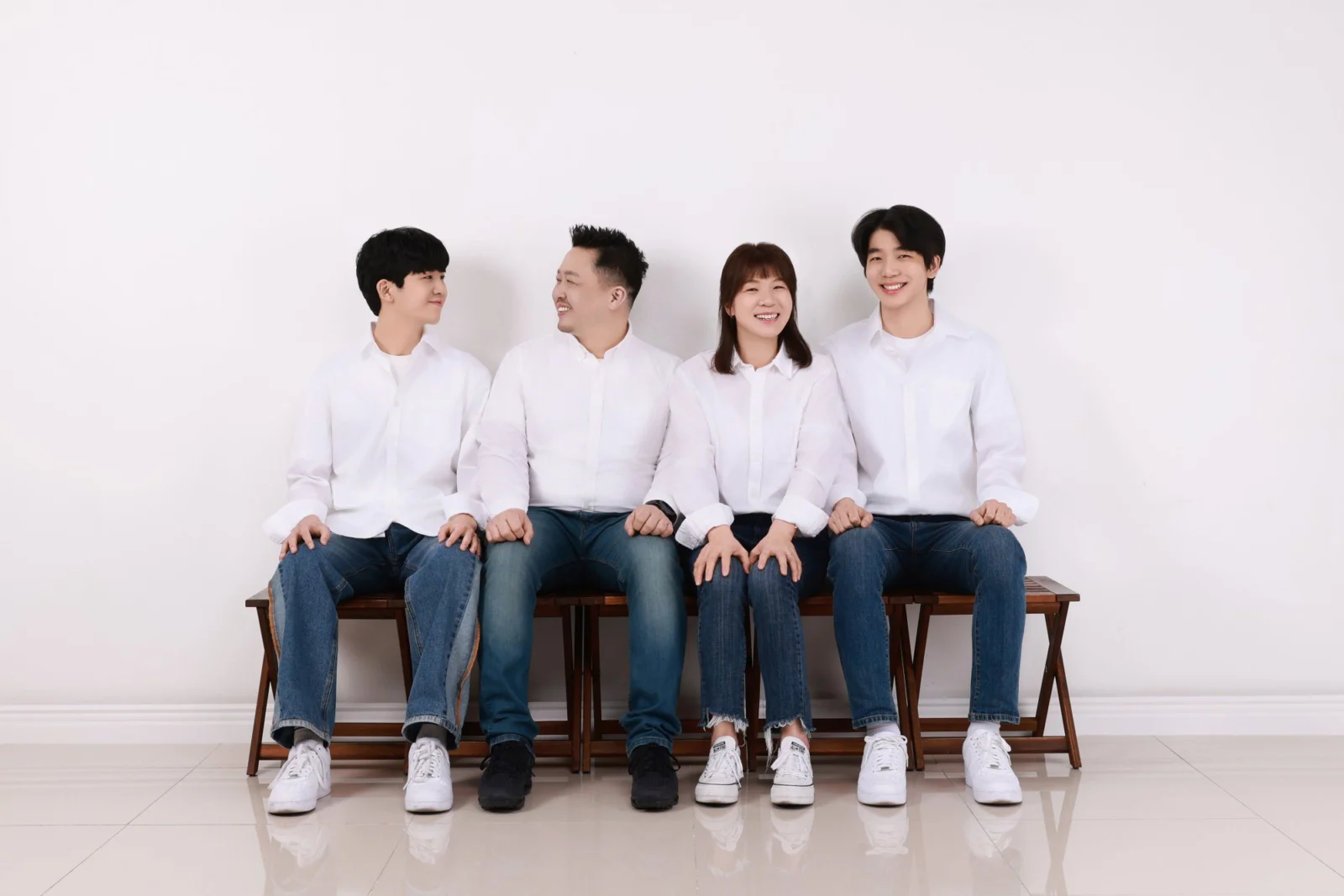 흰 셔츠를 맞춰 입고 벤치에 나란히 앉은 네 명의 가족사진