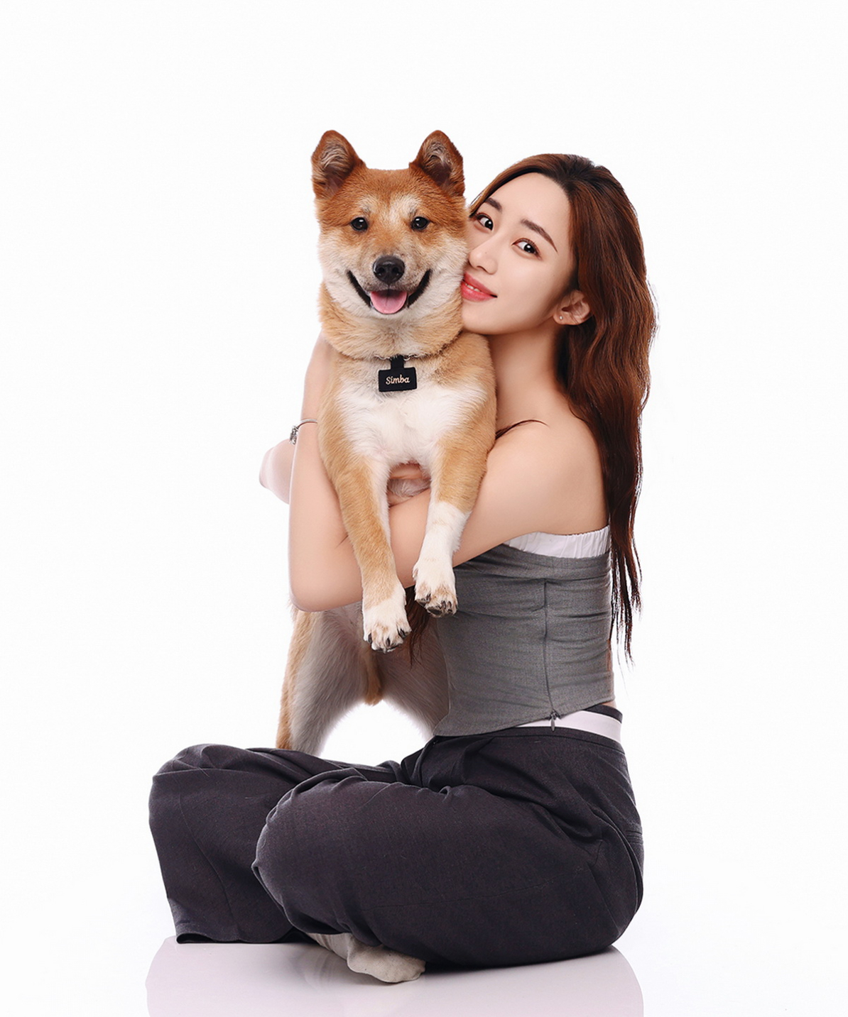 회색 상의 차림으로 바닥에 앉아 황갈색 강아지를 두 팔로 안은 인물