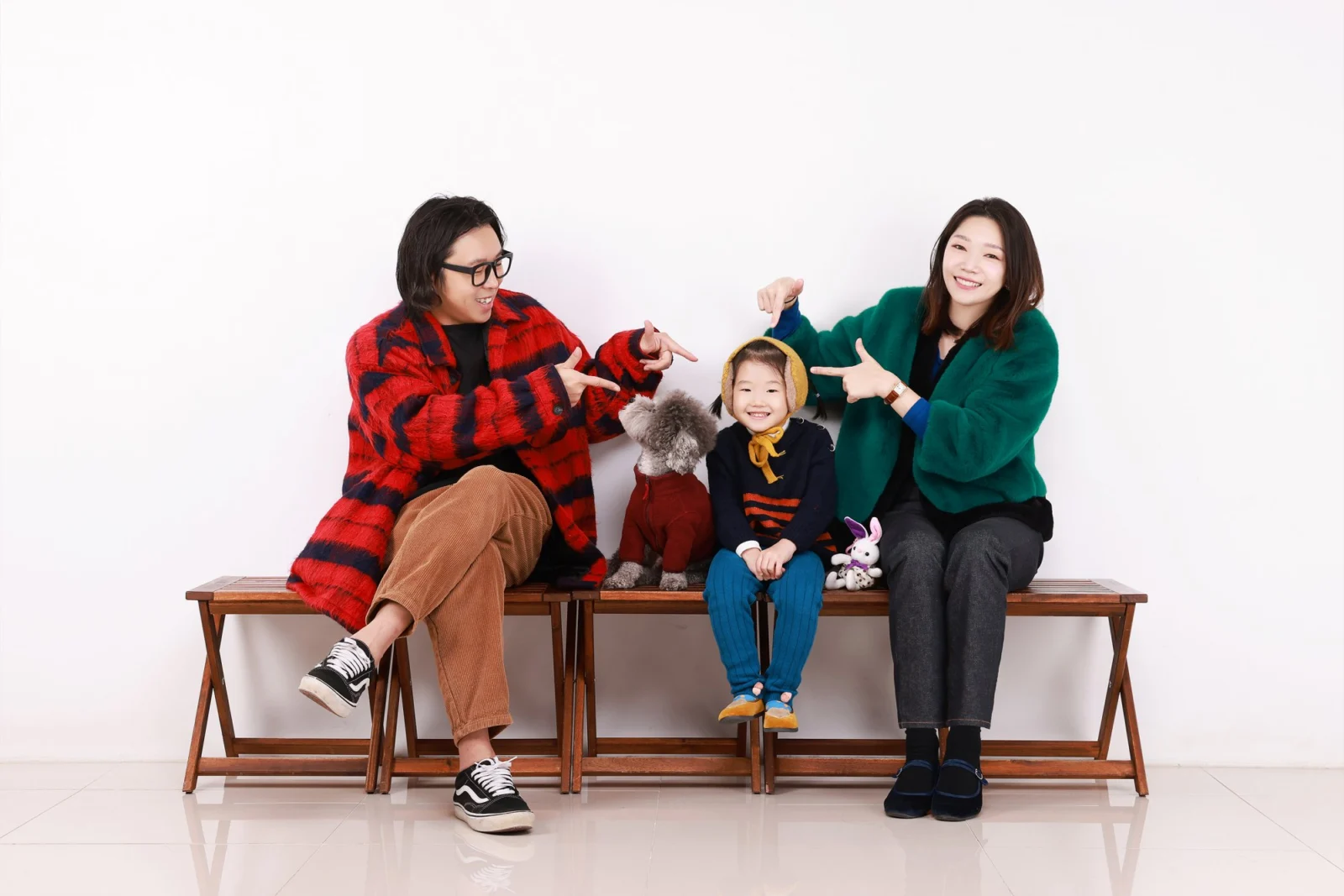 빨간 체크와 초록 옷 차림 두 사람이 벤치에서 아이와 강아지를 가리키는 개족사진