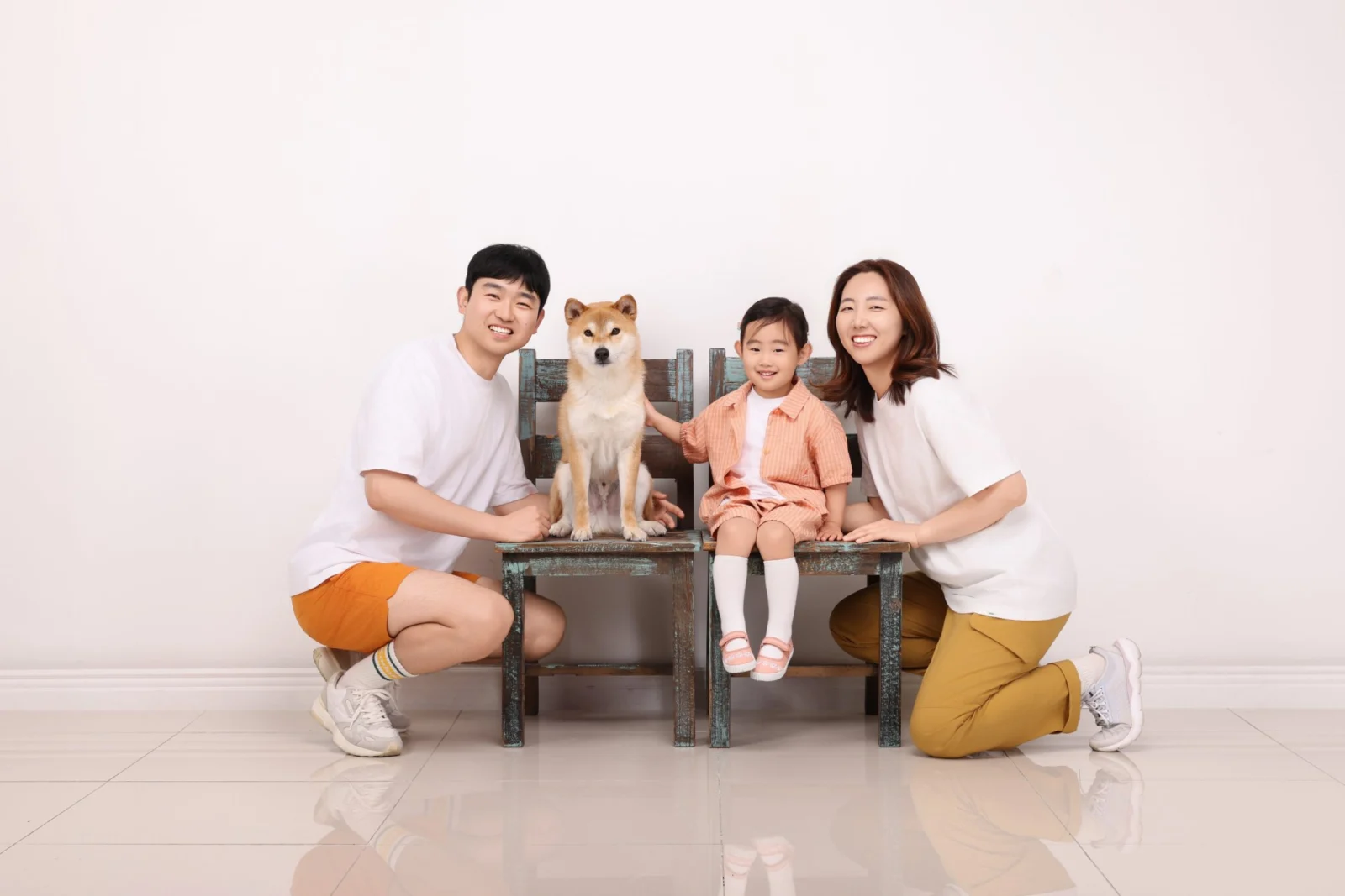 의자에 앉은 아이와 갈색 개 양옆에 앉은 두 사람의 개족사진