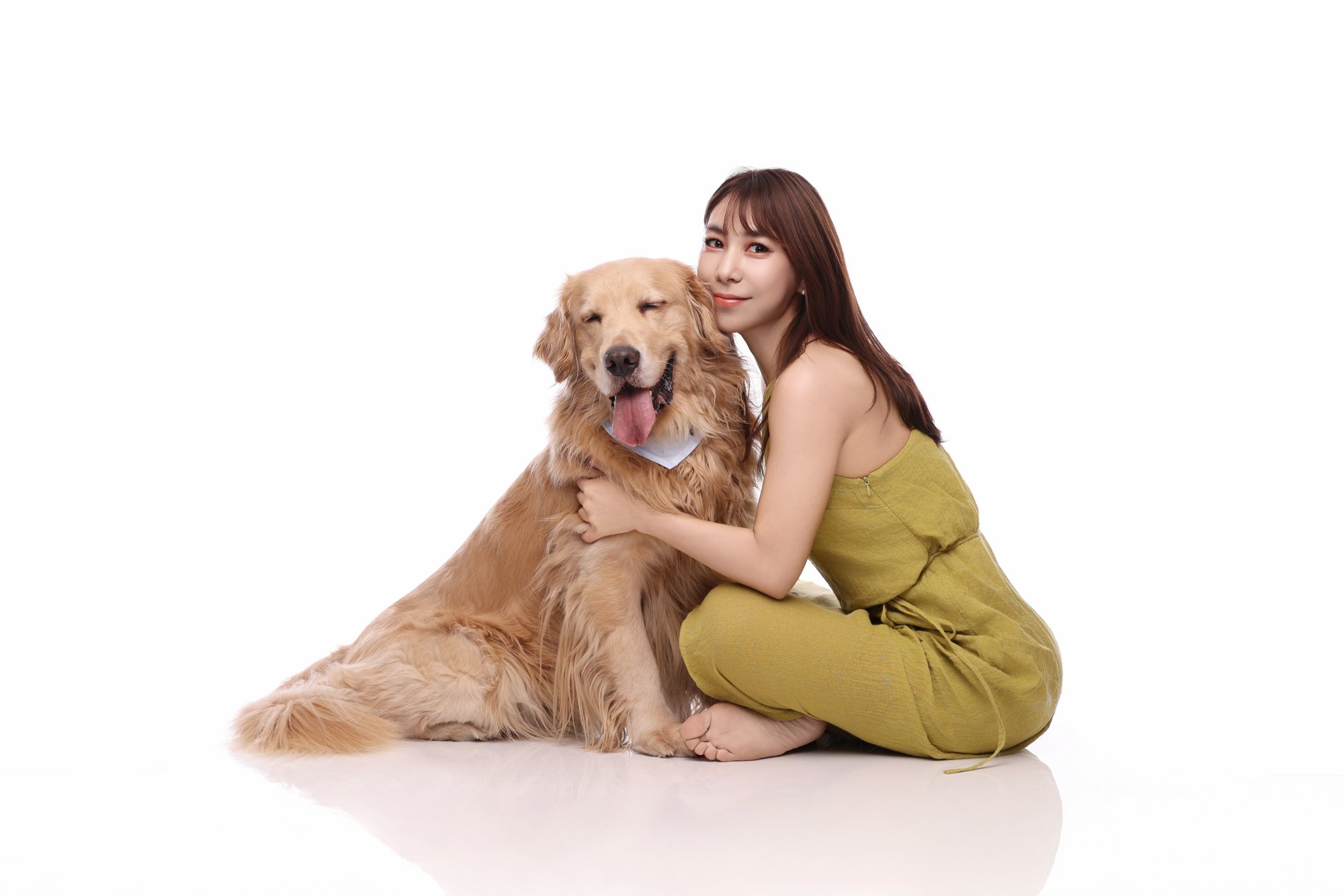 흰 배경 바닥에서 골든 리트리버를 안은 여성