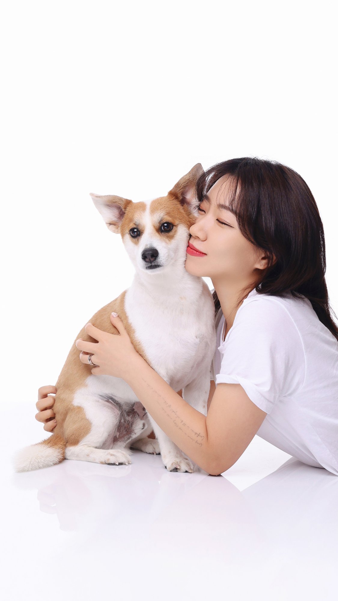 흰 티 차림으로 강아지에게 볼을 댄 여성