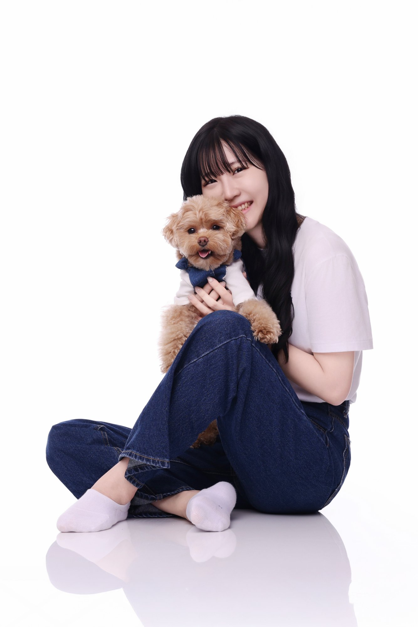 흰 양말 차림으로 갈색 푸들을 안고 웃는 여성