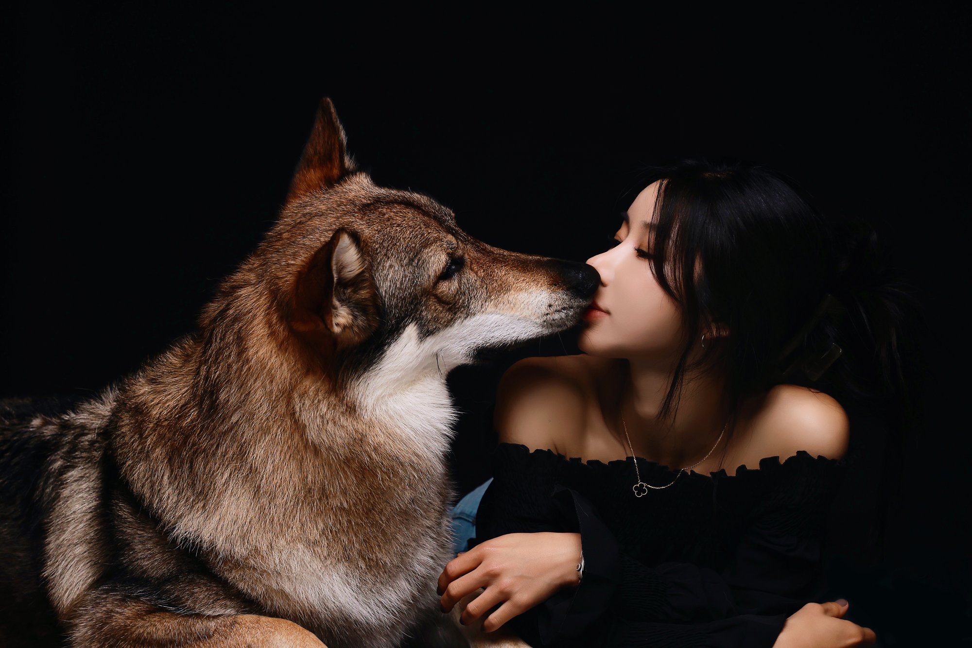 검정 배경에서 울프독과 코를 맞댄 여성