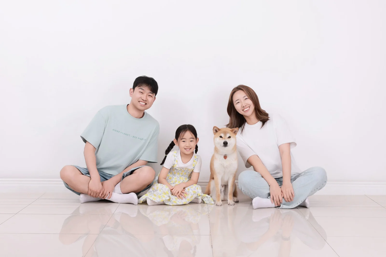 흰 바닥에 앉은 두 사람이 아이와 갈색 중형견을 사이에 둔 개족사진