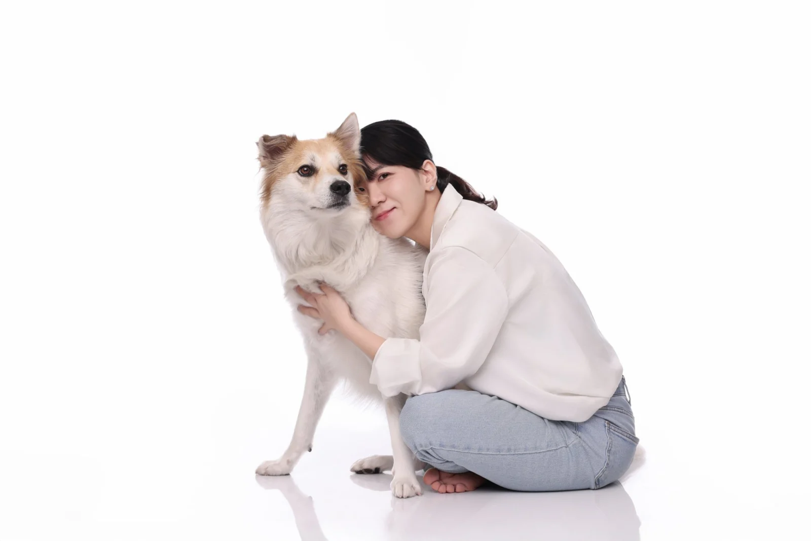 흰 바닥에 앉아 크림색 장모견에게 얼굴을 기댄 한 사람의 둘이함개 사진
