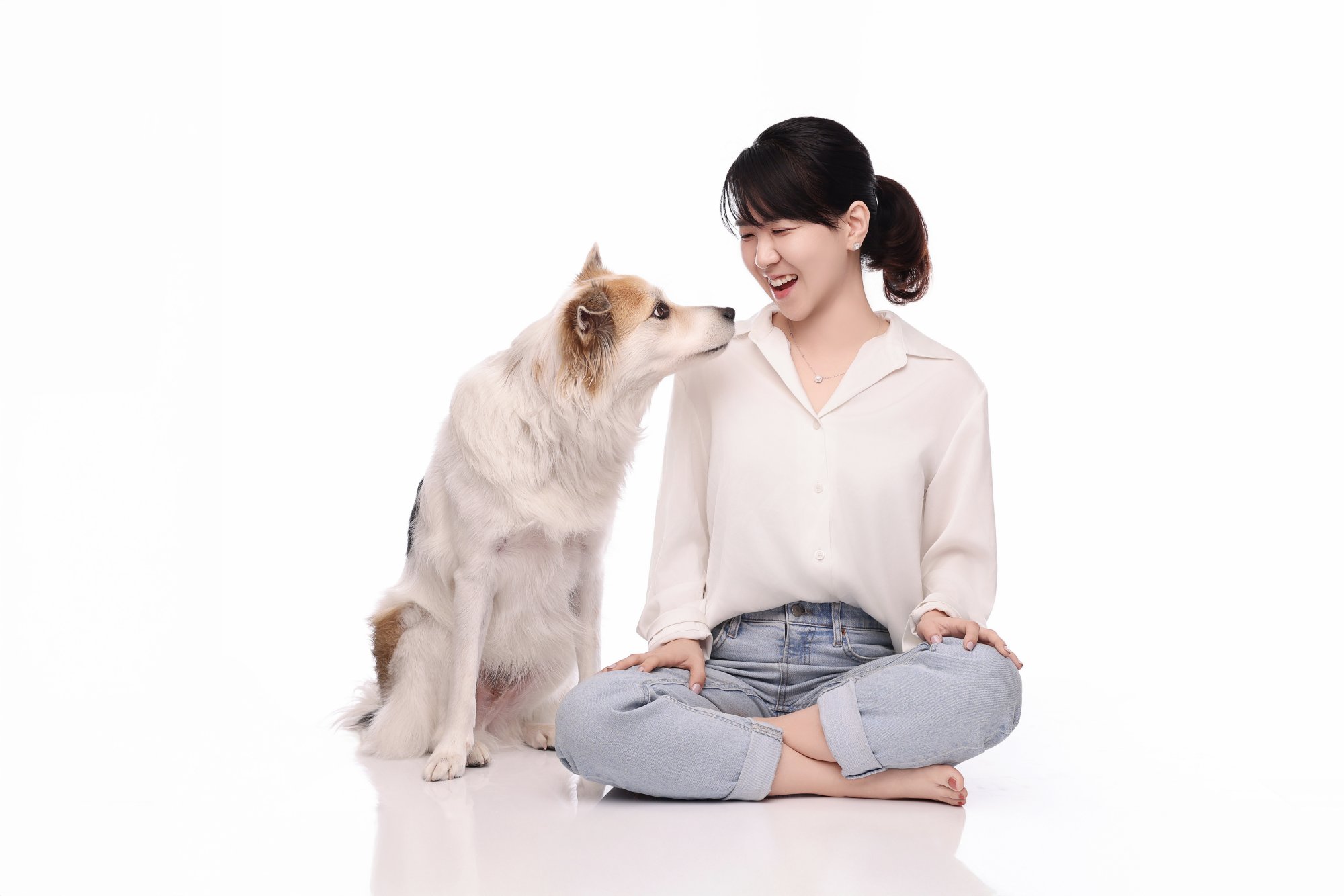 흰 장모견과 얼굴을 마주 보고 웃는 여성