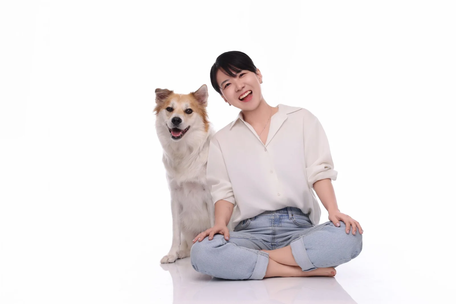 흰 배경 넓은 구도로 크림색 장모견 옆에 앉아 크게 웃는 둘이함개 사진