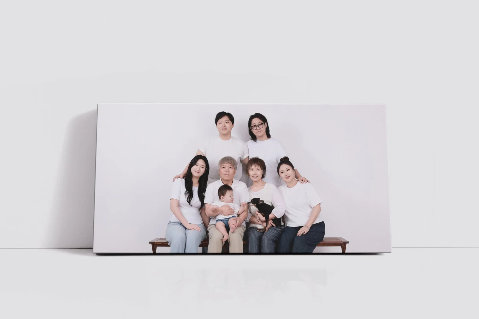 벤치에 앉고 선 일곱 명과 아기, 소형견의 개족사진을 넣은 가로 캔버스