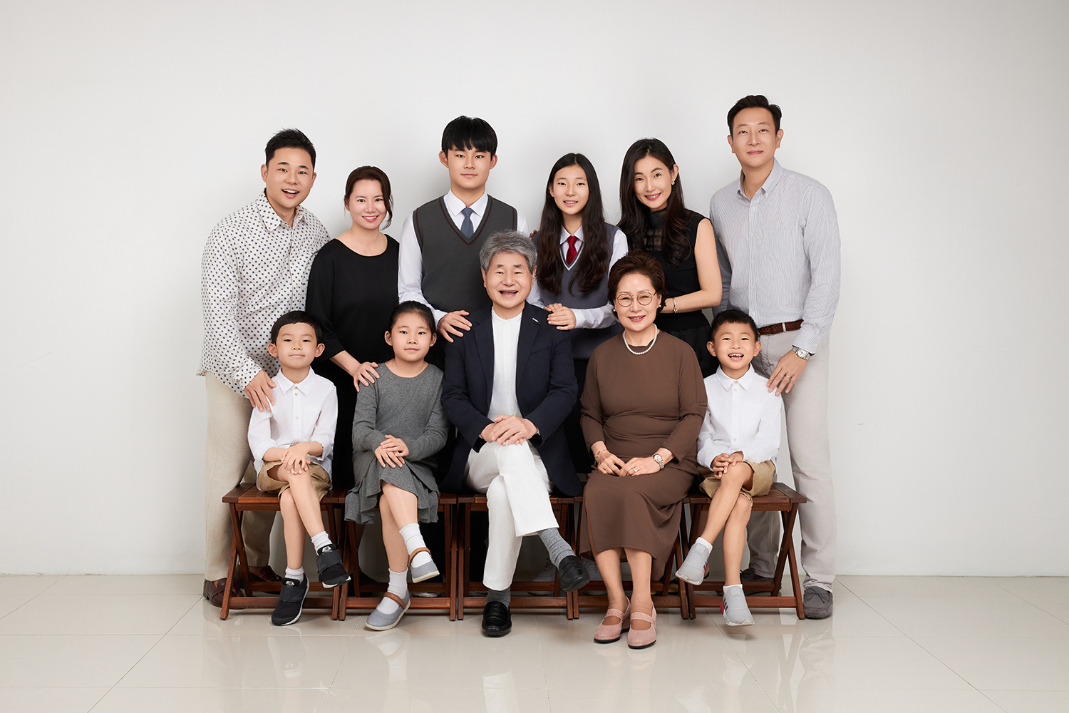 흰 벽 앞 나무 의자에 앉은 다섯 명과 뒤에 선 여섯 명의 열한 명 단체 사진