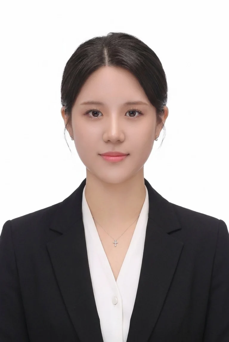 머리를 뒤로 넘겨 묶고 검은 재킷과 십자가 목걸이를 한 흰 배경 증명사진